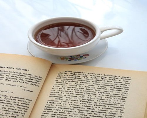 A hot cup of tea and a book resting on a table, symbolizing a relaxing break